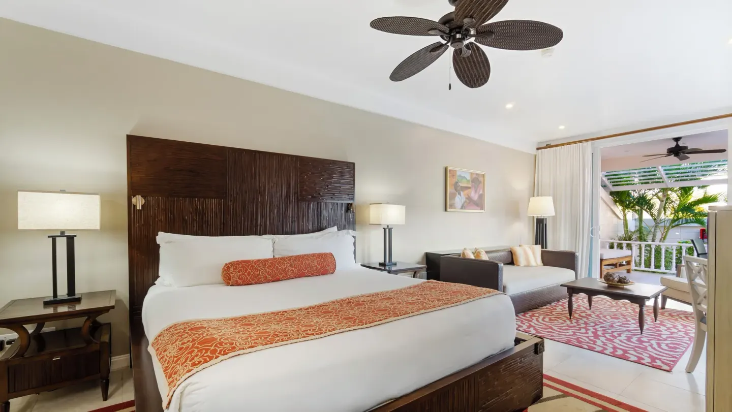Anthurium Pool Suite king bed and sitting area at Spice Island Beach Resort.