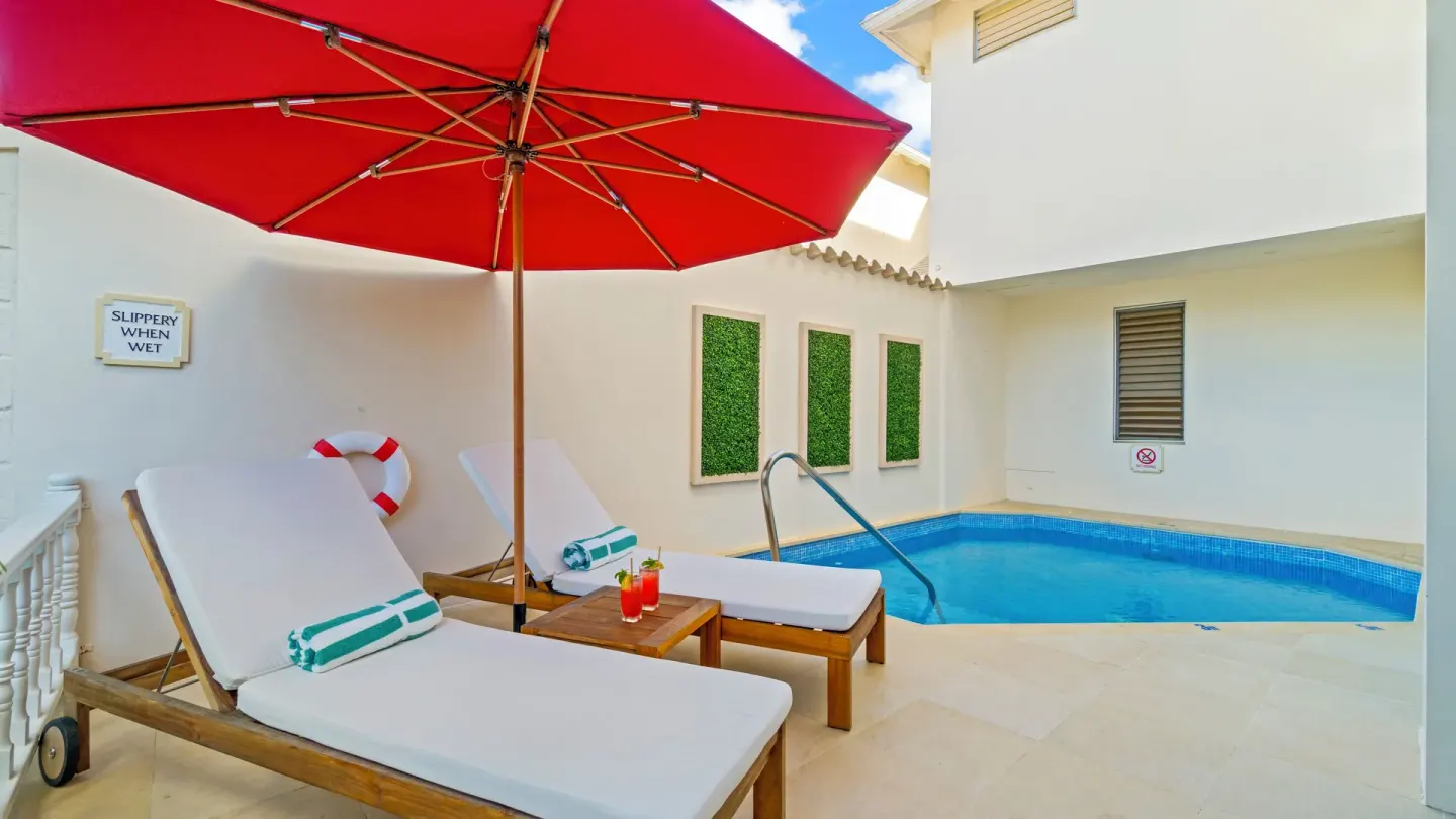 Private pool terrace with loungers and red umbrella at Spice Island Beach Resort.