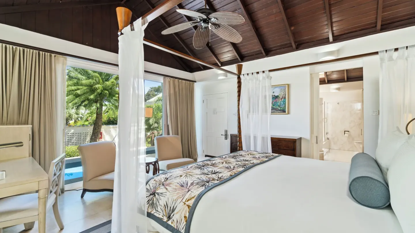 Luxury Almond Pool Suite bedroom with four-poster bed at Spice Island Beach Resort.