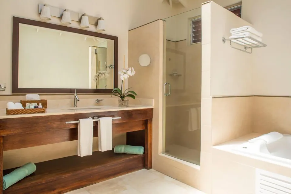 Oleander Garden Suite bathroom with vanity, shower, and tub at Spice Island Beach Resort.