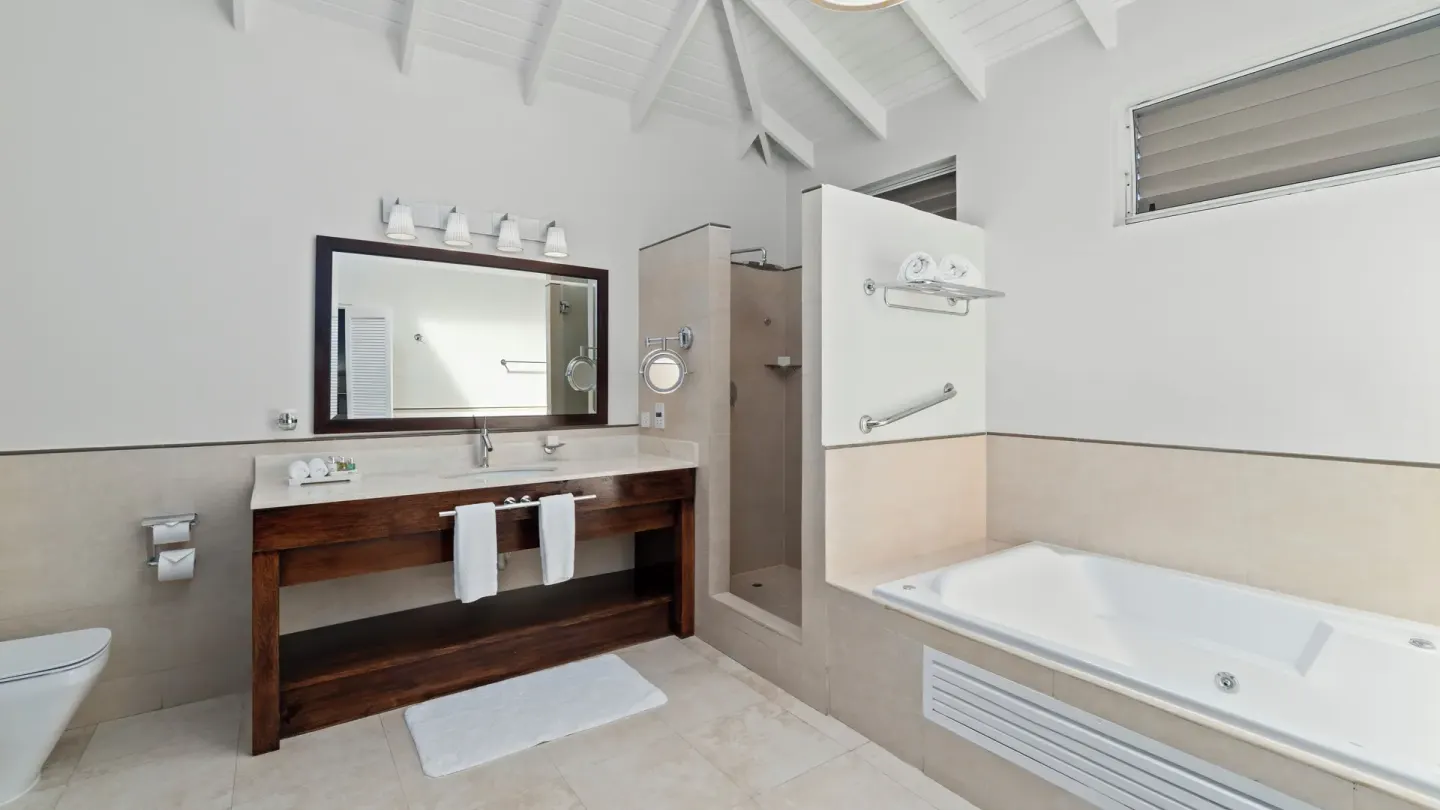 Oleander Garden View Suite bathroom with vanity, shower, and tub at Spice Island Beach Resort.