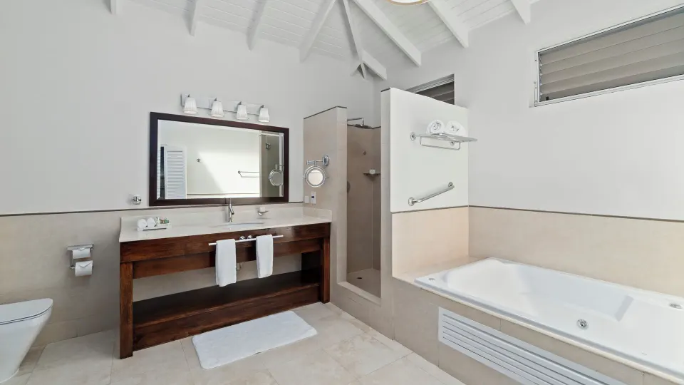 Oleander Garden View Suite bathroom with vanity, shower, and tub at Spice Island Beach Resort.
