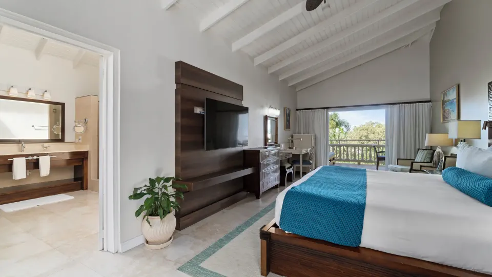 Oleander Garden View Suite with king bed, TV wall, bathroom, and balcony at Spice Island Beach Resort.