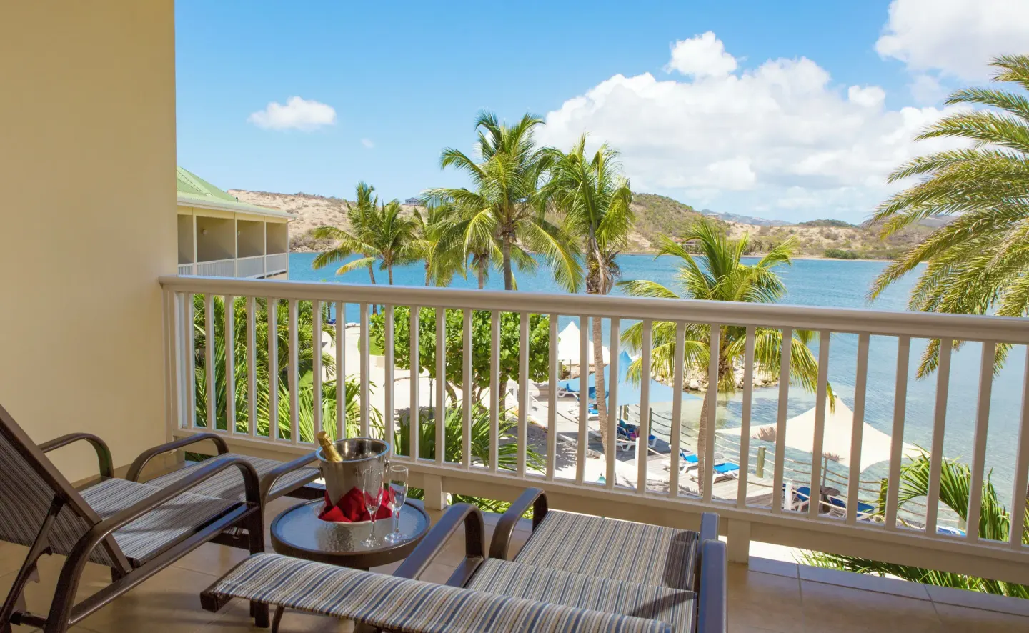 Balcony lounge chairs with bay and palm views at St. James's Club Antigua.