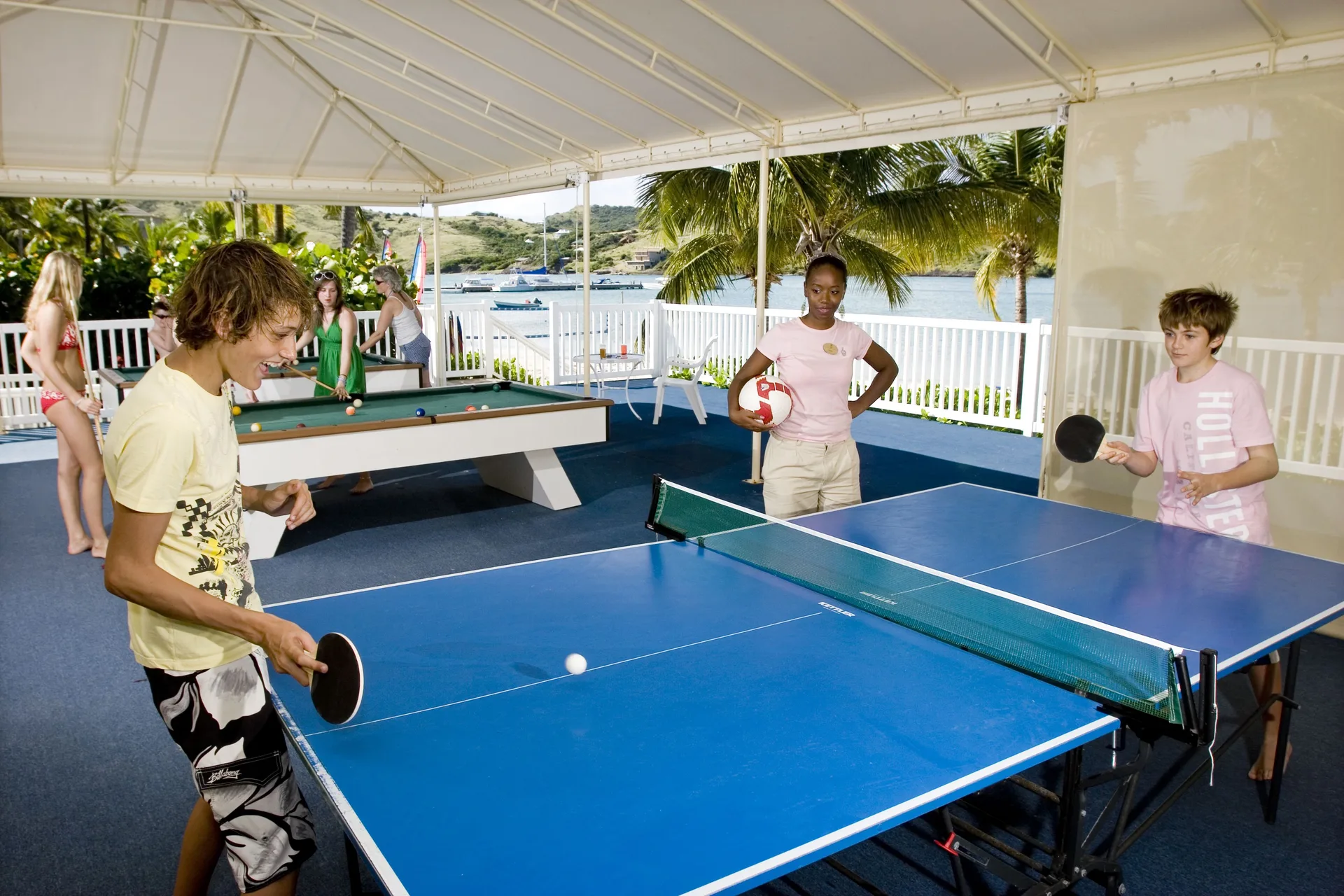 Teens playing table tennis and pool in a covered games area at St. James's Club Antigua.