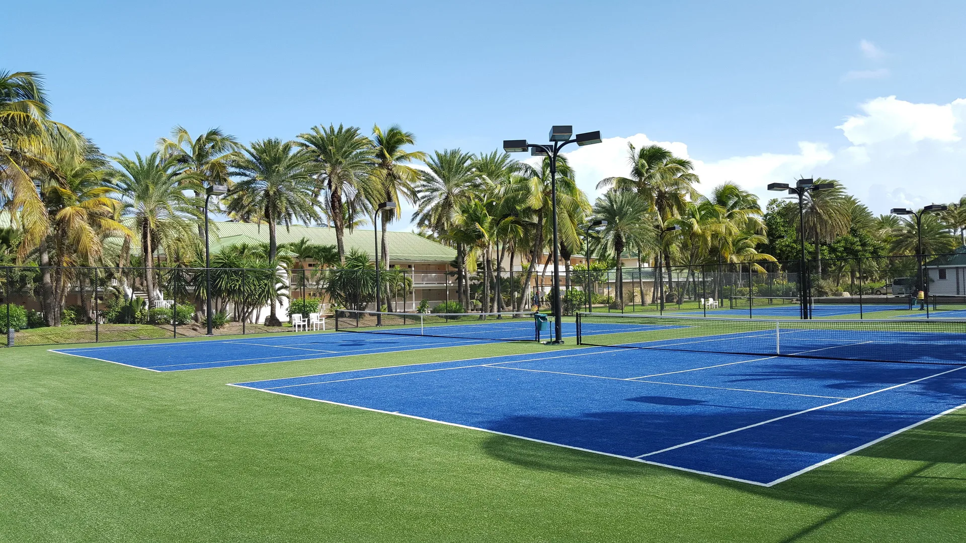 Blue tennis courts surrounded by palm trees at St. James's Club Antigua.