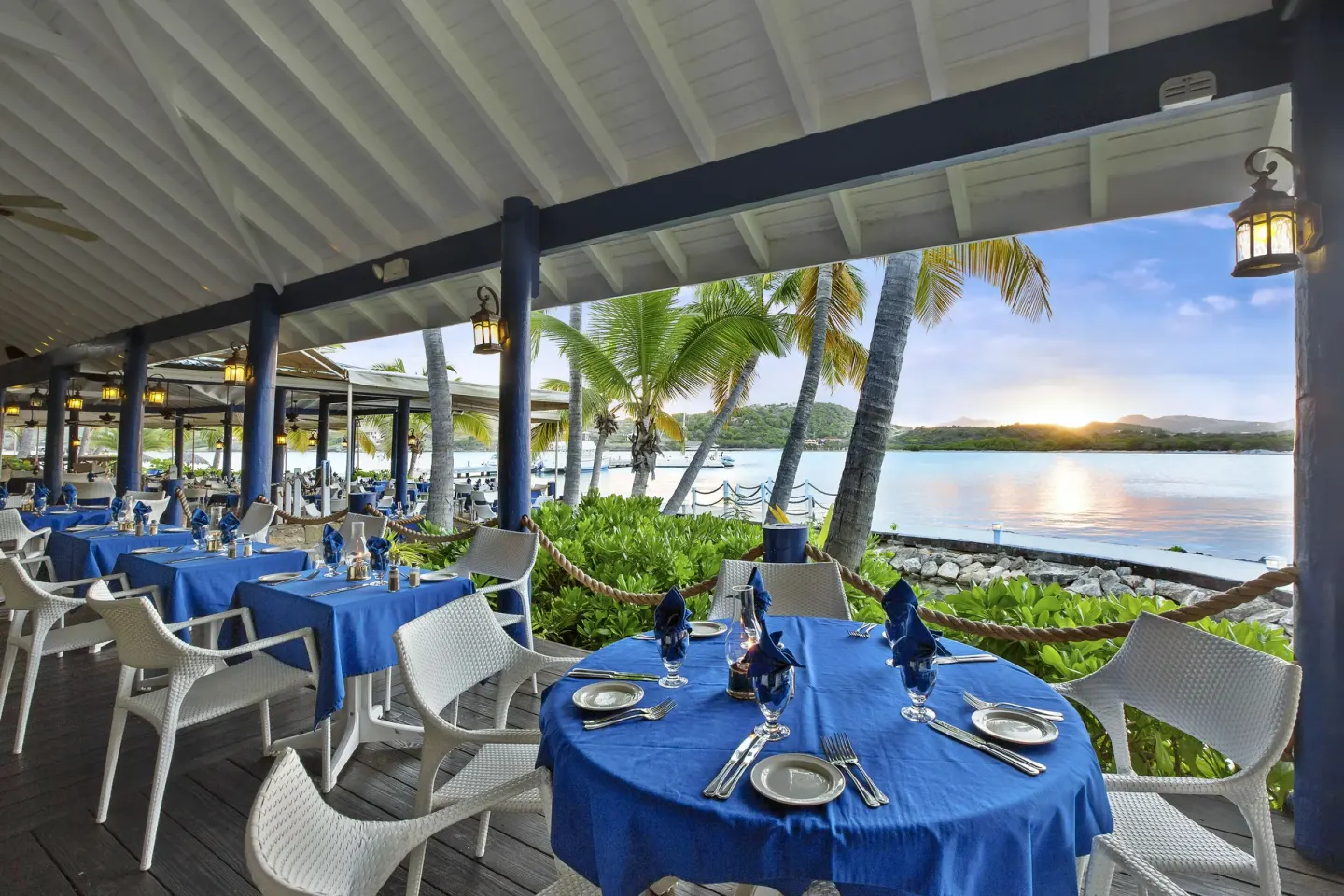 Open-air waterfront dining tables at sunset at St. James's Club Antigua.