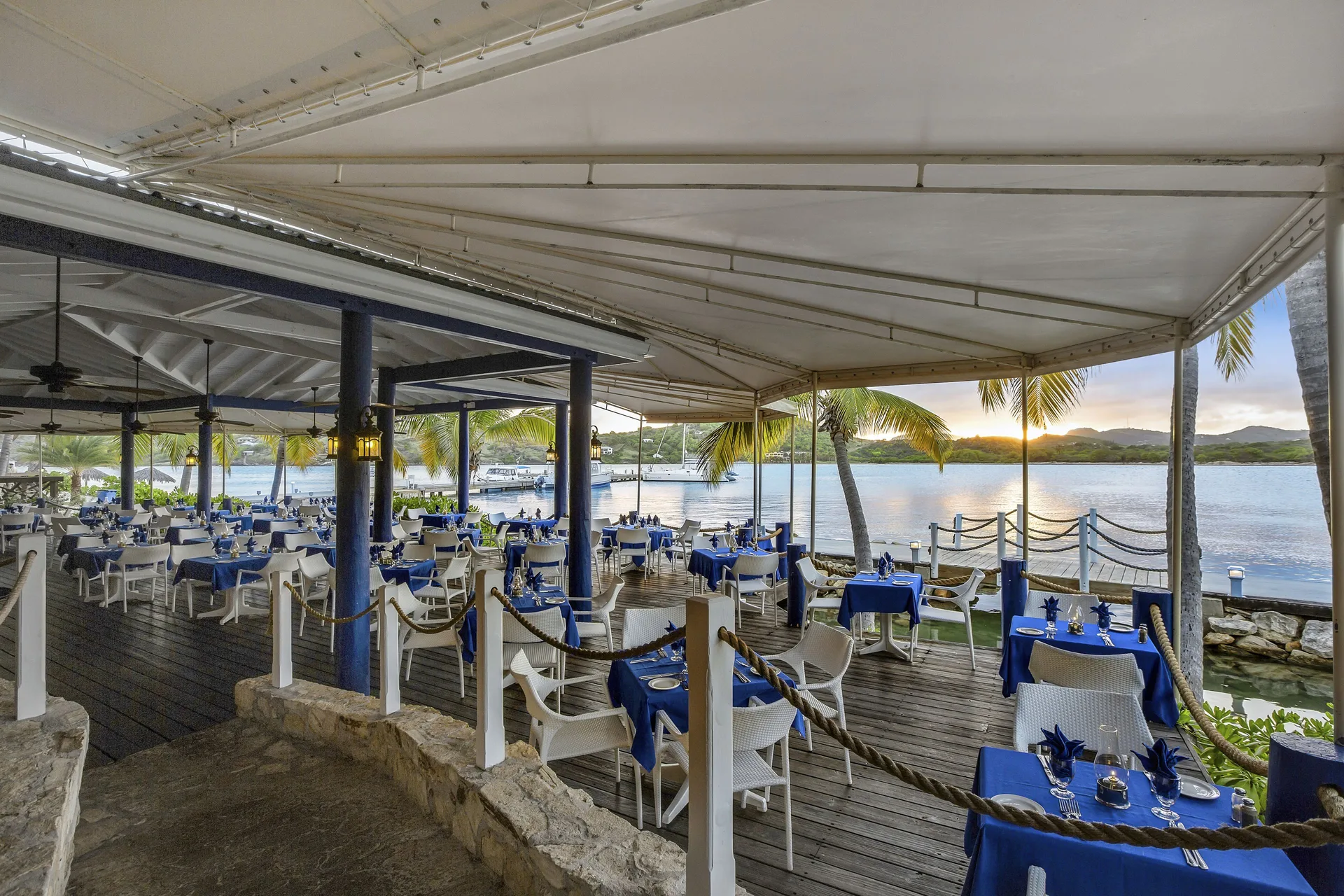 Waterfront restaurant deck with blue table settings at St. James's Club Antigua.