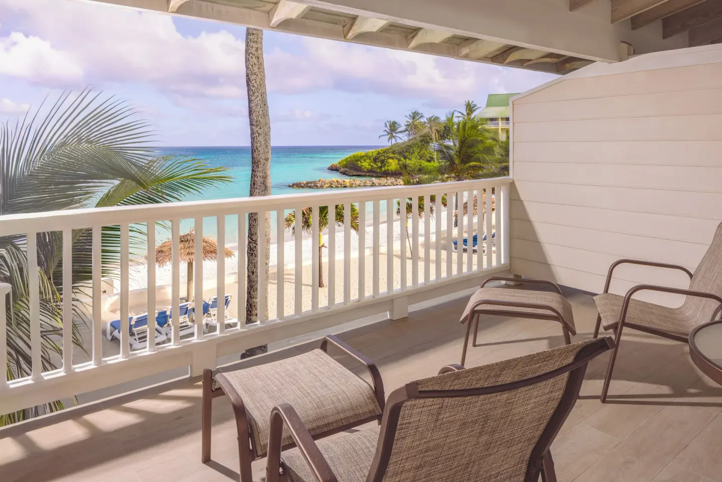 Beachfront Room balcony seating overlooking beach and palms at St. James's Club Antigua.