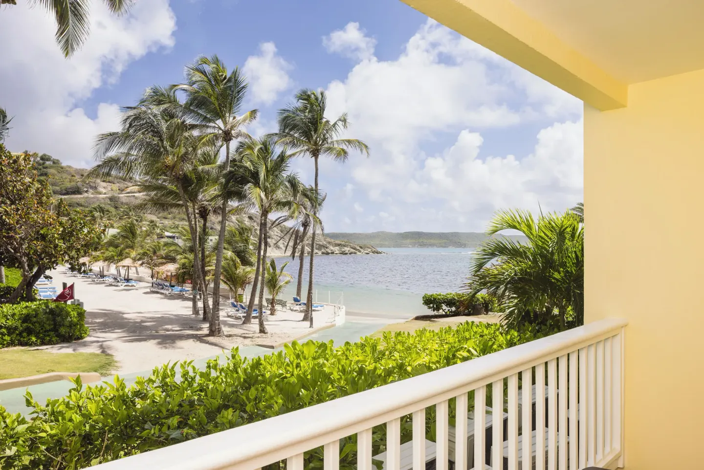 Club Room balcony view of palms, beach, and bay at St. James's Club Antigua.