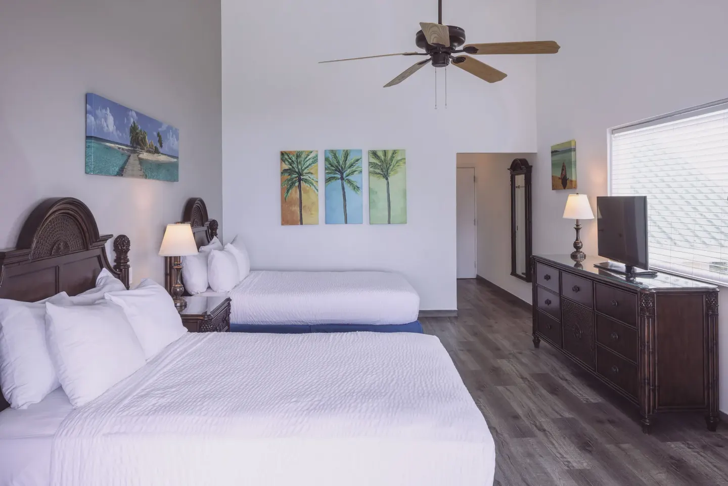 Premium Room with two beds, high ceiling, TV, and palm artwork at St. James's Club Antigua.