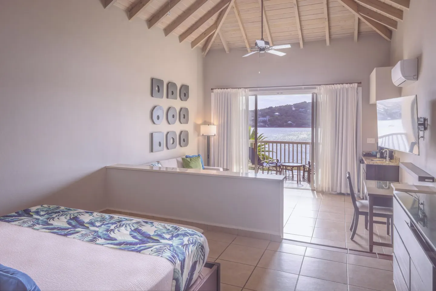 Royal Suite king bed, vaulted ceiling and water-view balcony at St. James's Club Antigua.