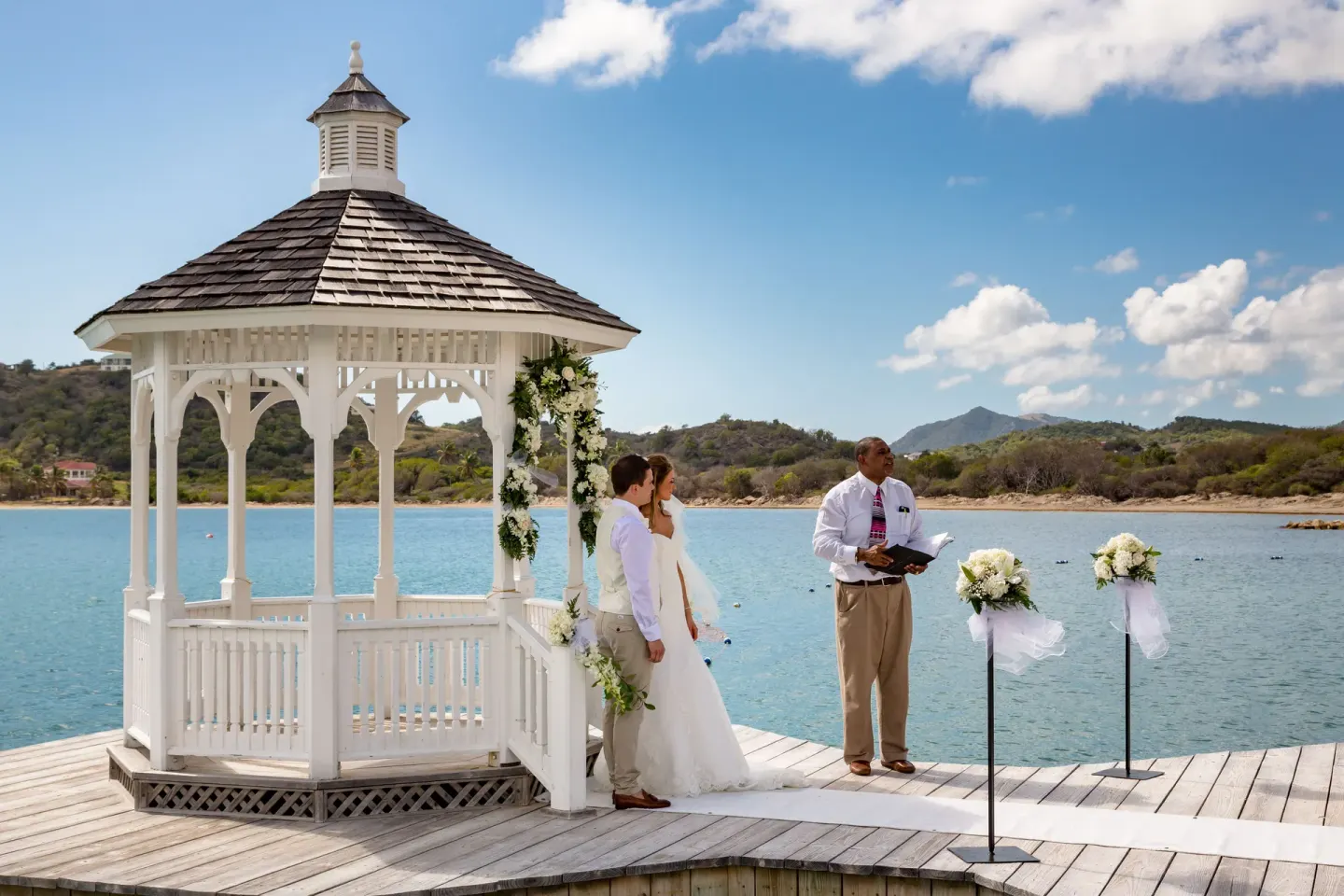 Wedding ceremony by a white gazebo over the water at St. James's Club Antigua.