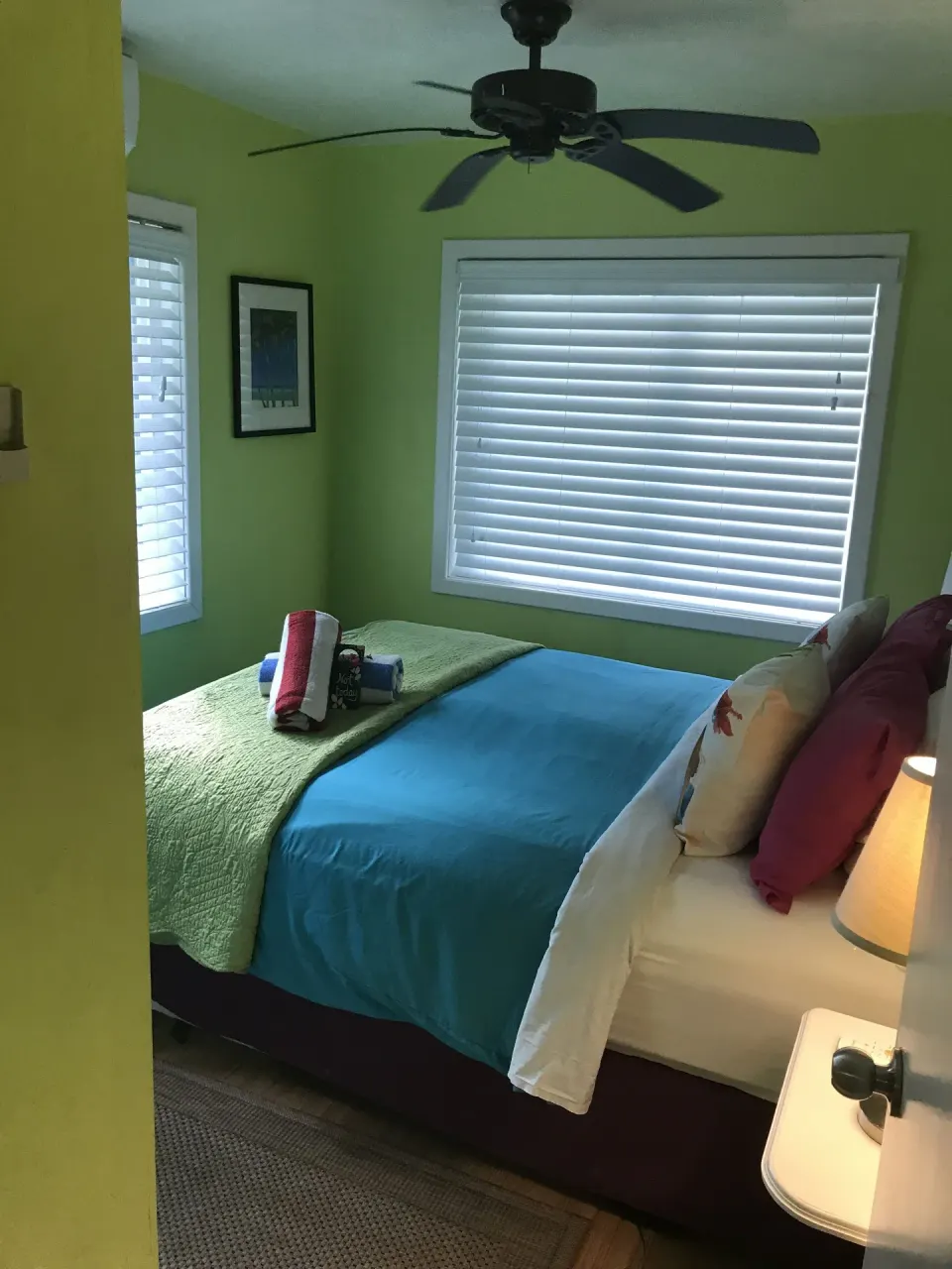 Green guest room with blue bedding and shuttered windows at St John Inn.