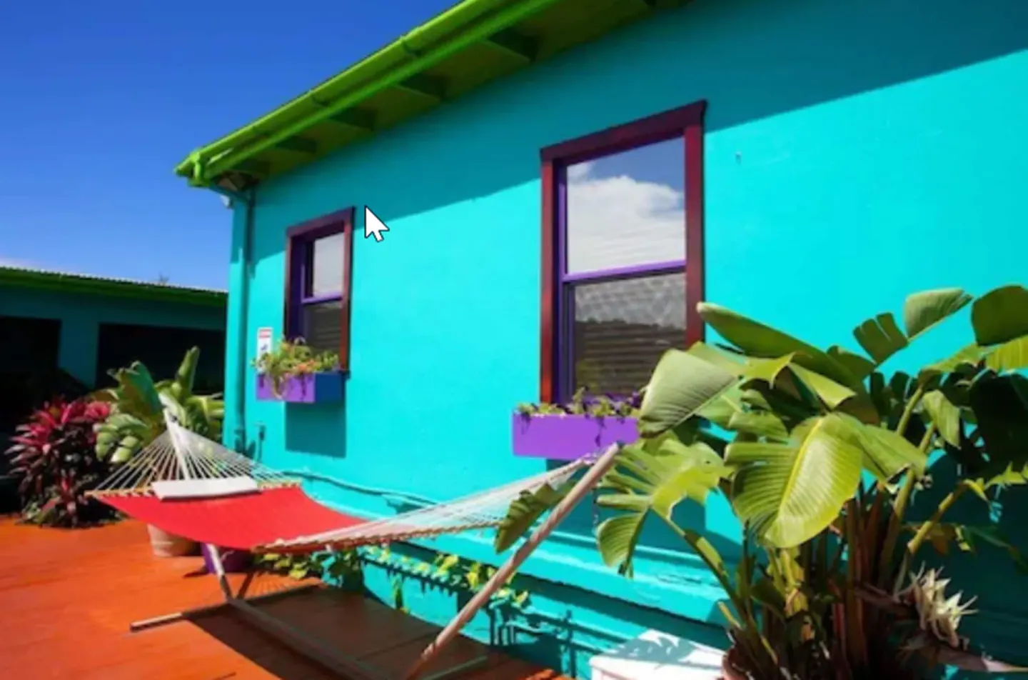 Red hammock beside turquoise walls and tropical plants at St John Inn.