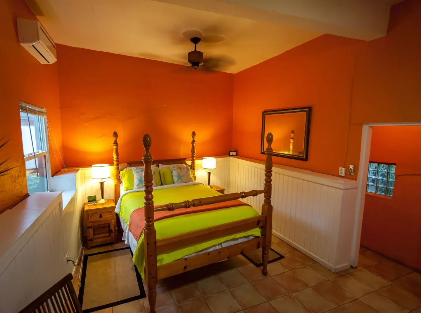 Orange guest room with four-poster bed and bedside lamps at St John Inn.