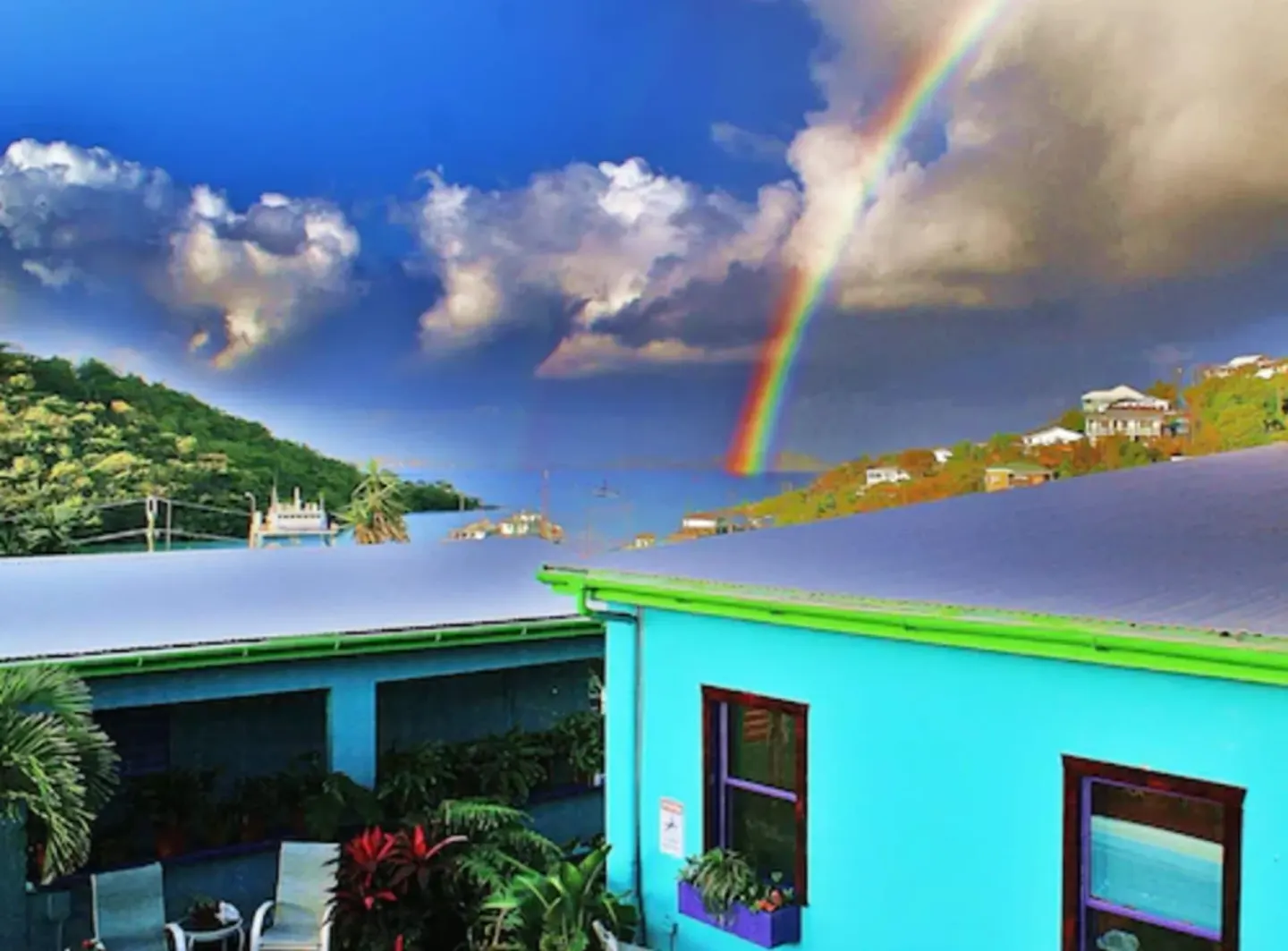 Rainbow over turquoise buildings and hillside at St John Inn.