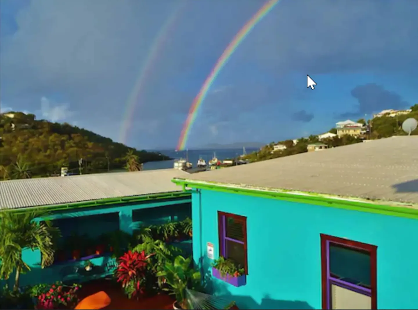 Double rainbow over turquoise buildings and harbor hillside at St John Inn.