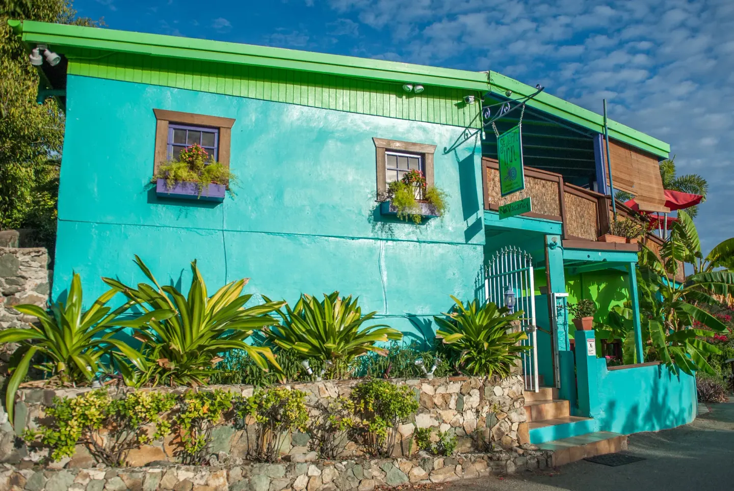 Street-side turquoise building with flower boxes and entry gate at St John Inn.