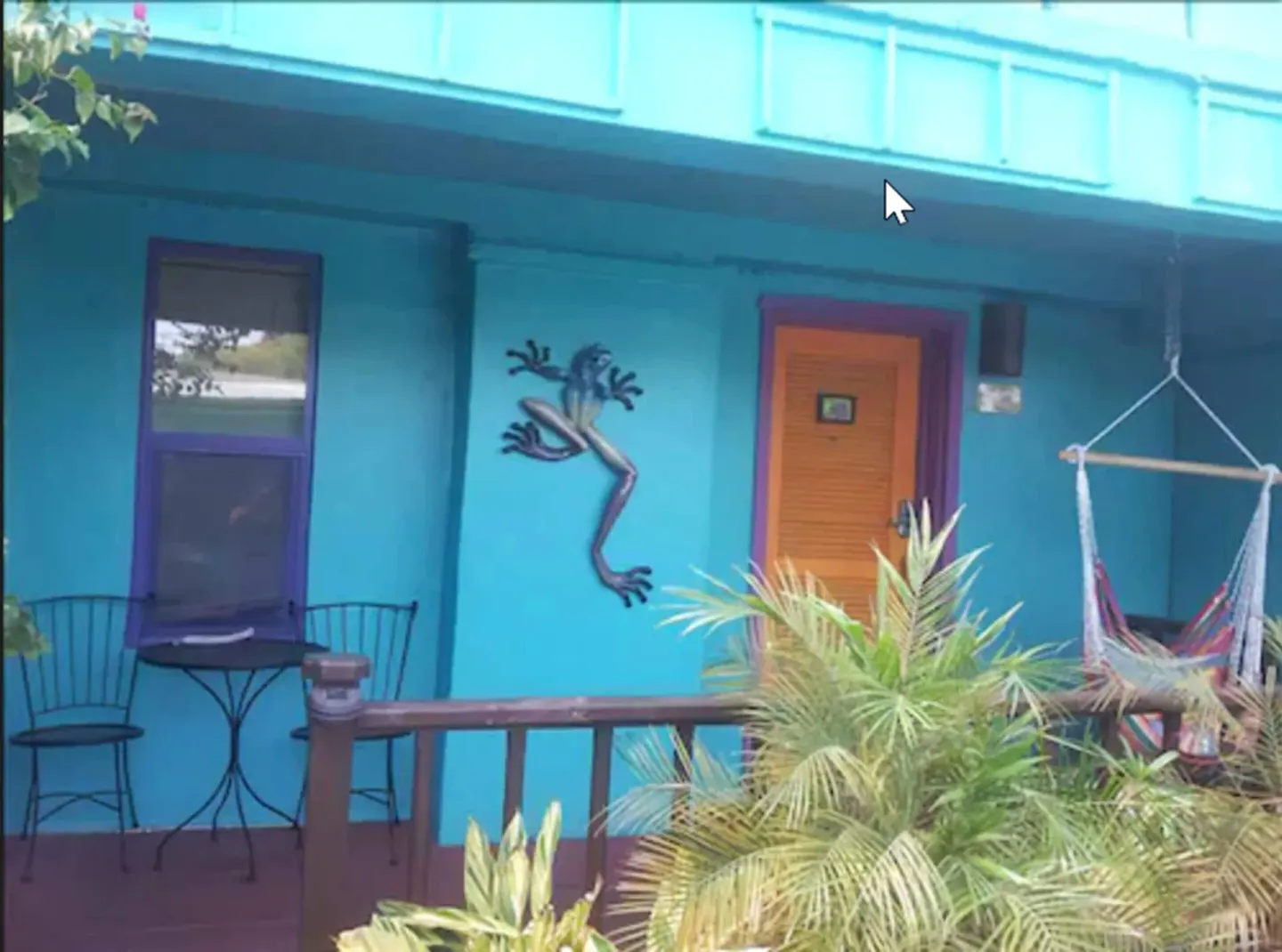 Turquoise exterior porch with chairs, hammock chair, and lizard wall art at St John Inn.