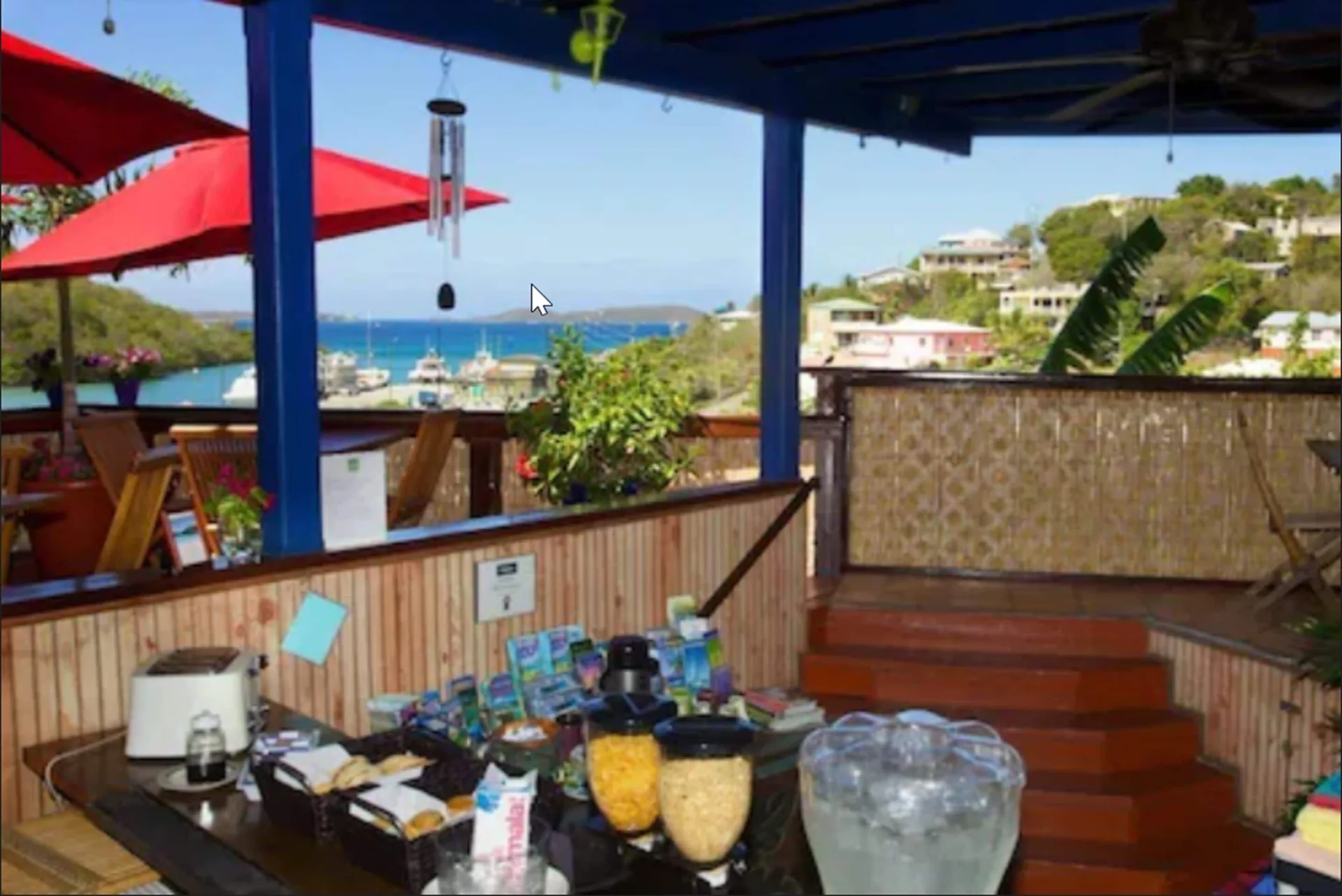 Covered breakfast area with harbor view and red umbrellas at St John Inn.
