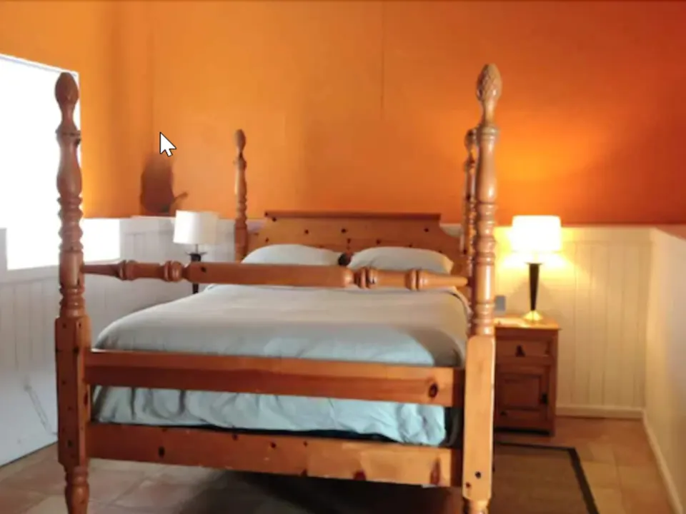 Standard Room four-poster bed against orange walls at St John Inn.