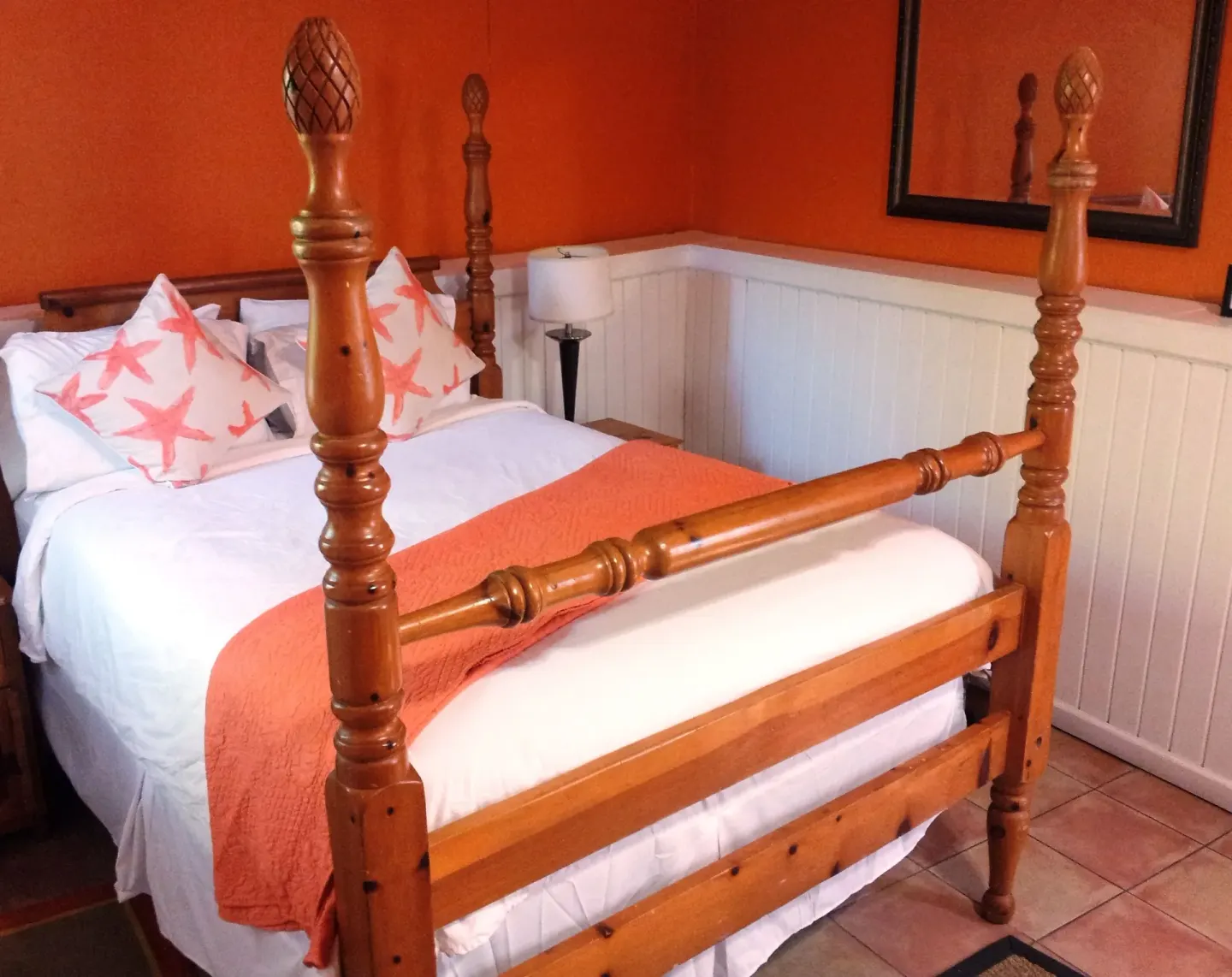 Standard Room four-poster bed with coral pillows and throw at St John Inn.