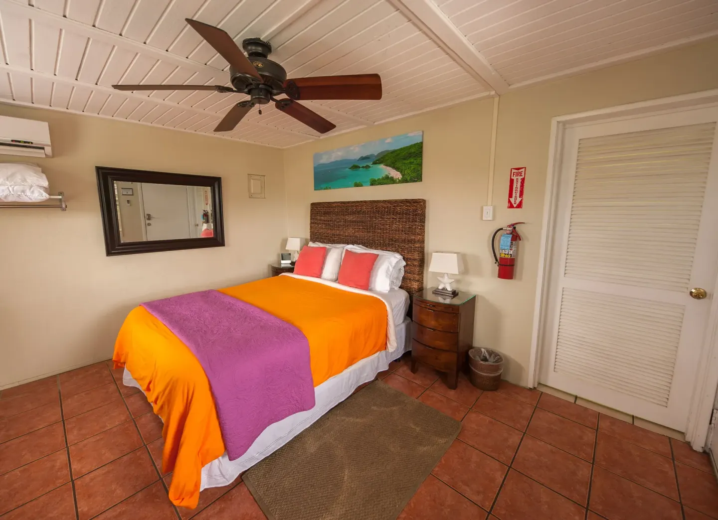 Standard Room bed with orange coverlet and purple throw at St John Inn.