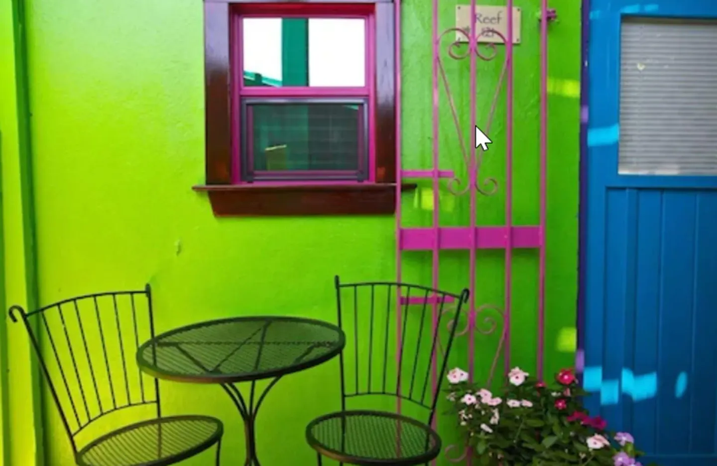 Standard Room exterior patio with table, chairs, blue door, and green wall at St John Inn.