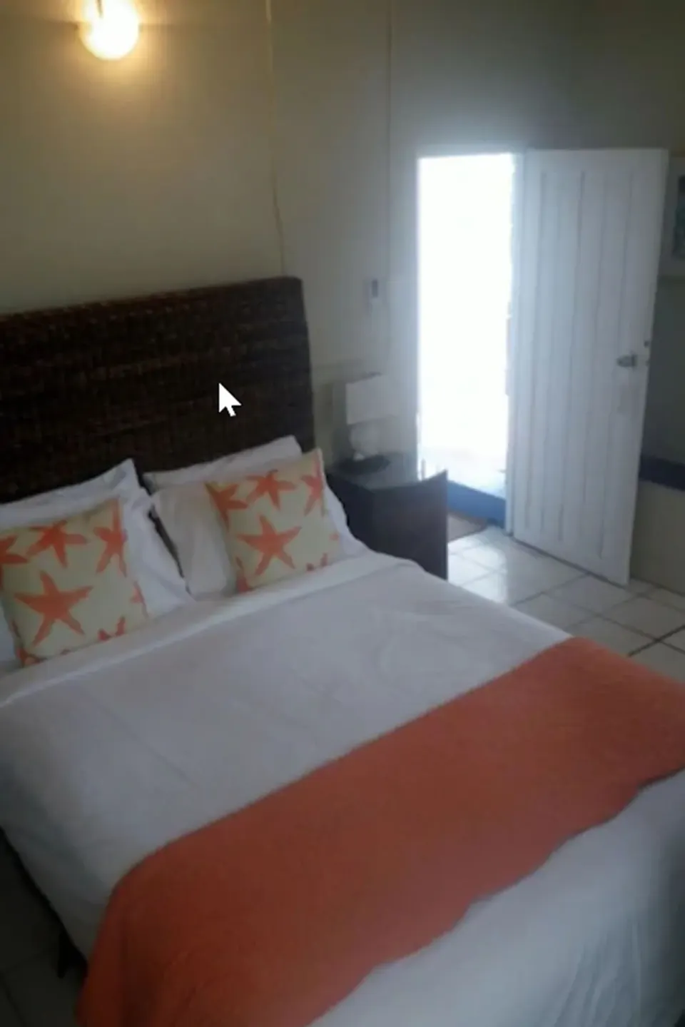 Bedroom in a two-bedroom suite at St John Inn with white bedding, starfish pillows, and an open door.