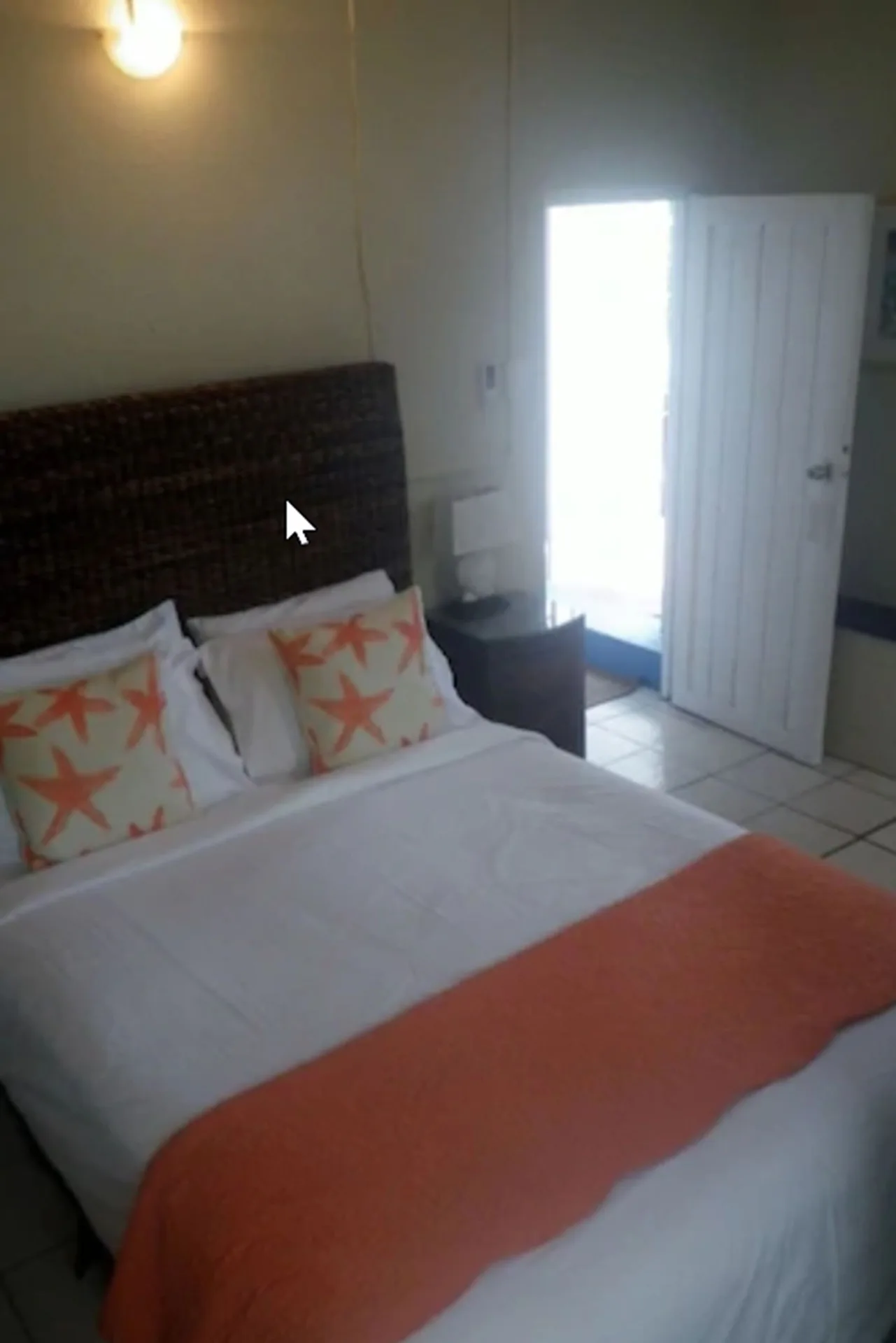 Bedroom in a two-bedroom suite at St John Inn with white bedding, starfish pillows, and an open door.