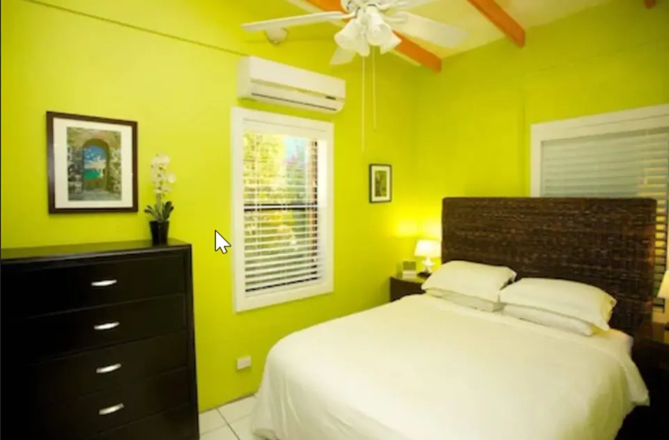 Suite bedroom with bed, dresser, ceiling fan, and green walls at St John Inn.