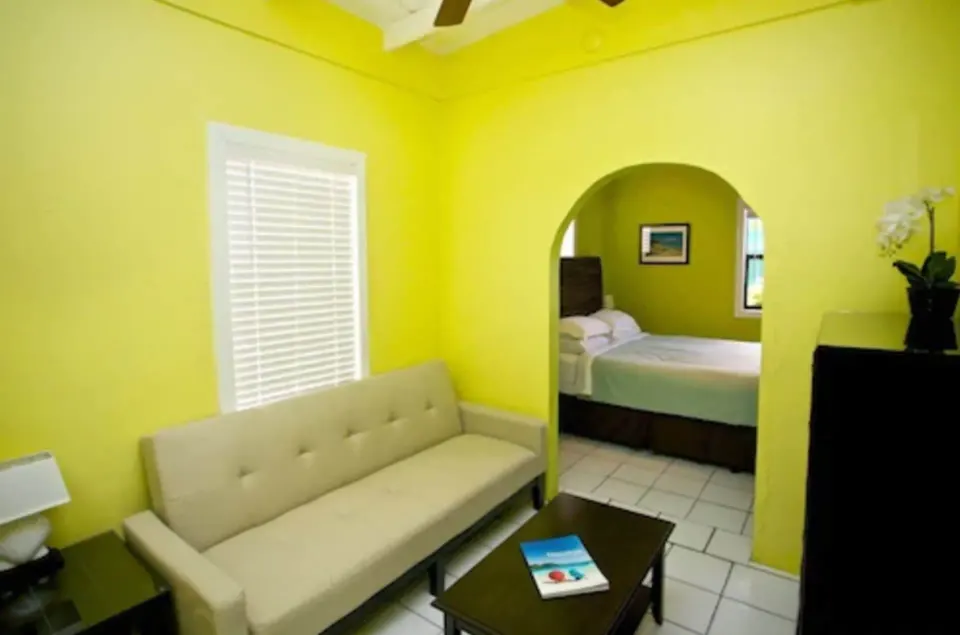 Suite living area with sofa bed, coffee table, and bedroom through an arch at St John Inn.