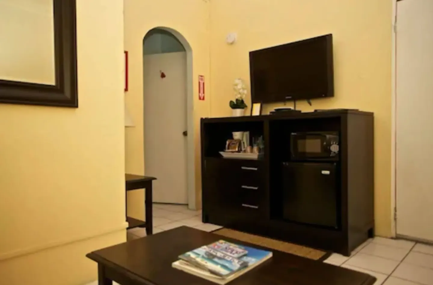Suite living area with TV cabinet, mini fridge, microwave, and coffee table at St John Inn.