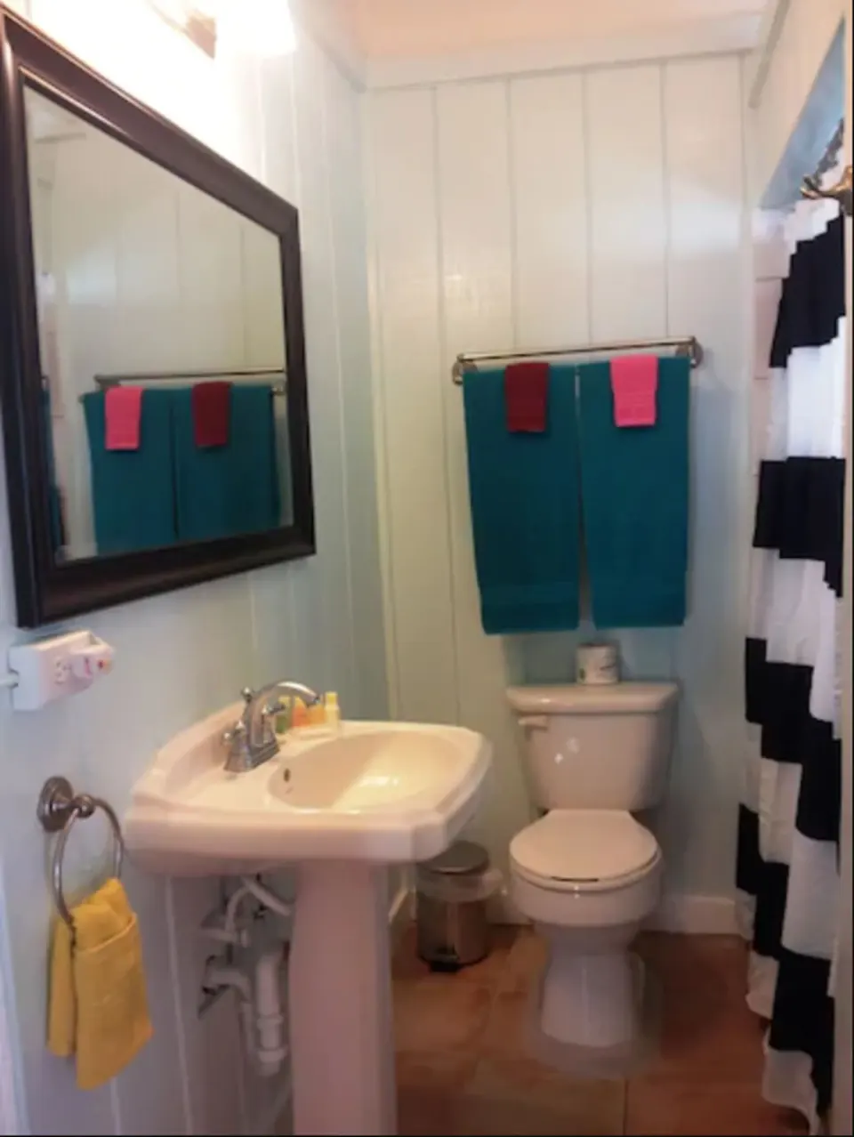 Superior Suite bathroom with pedestal sink, toilet, towels, and striped shower curtain at St John Inn.