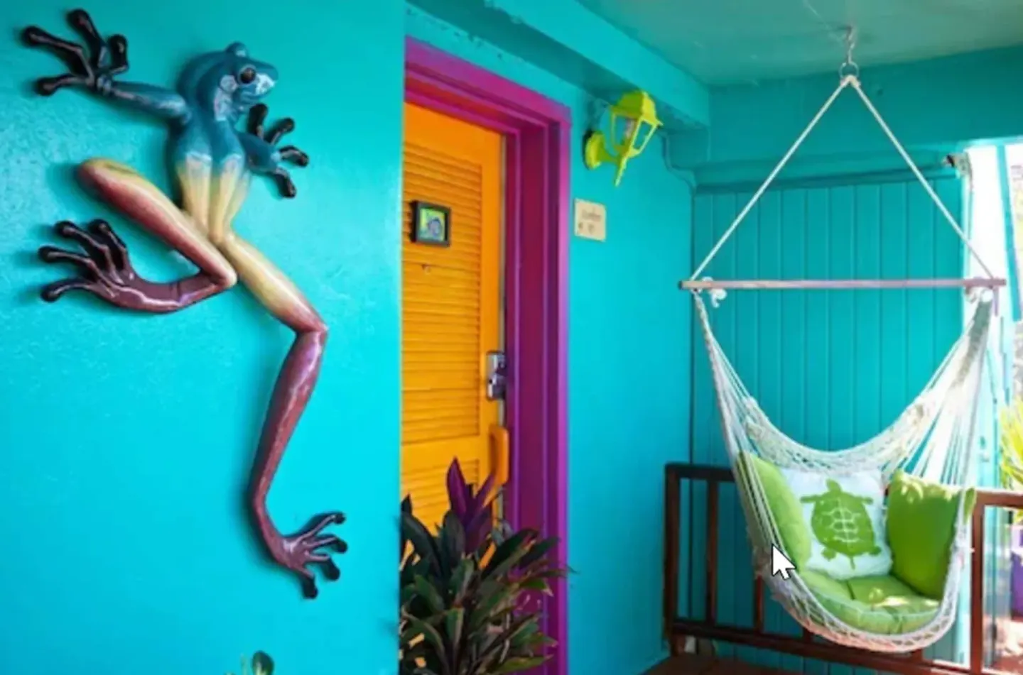 Superior Suite porch with hammock chair, bright door, and frog wall art at St John Inn.