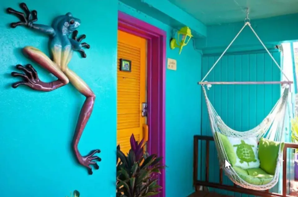 Superior Suite porch with hammock chair, bright door, and frog wall art at St John Inn.