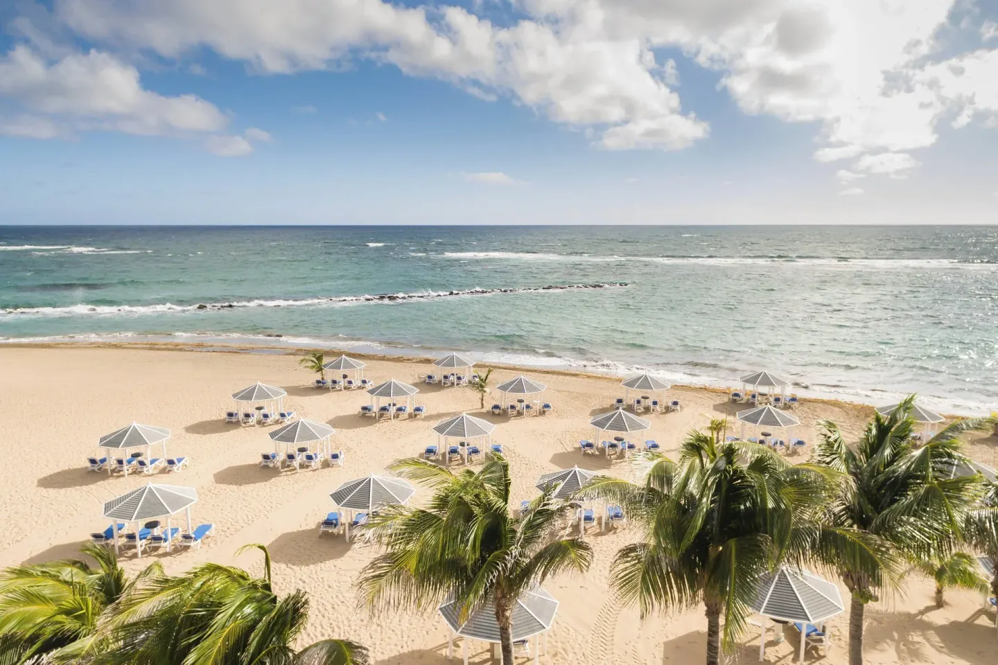 Aerial beach view with cabanas and palm trees at St Kitts Marriott Beach Resort, Casino & Spa.