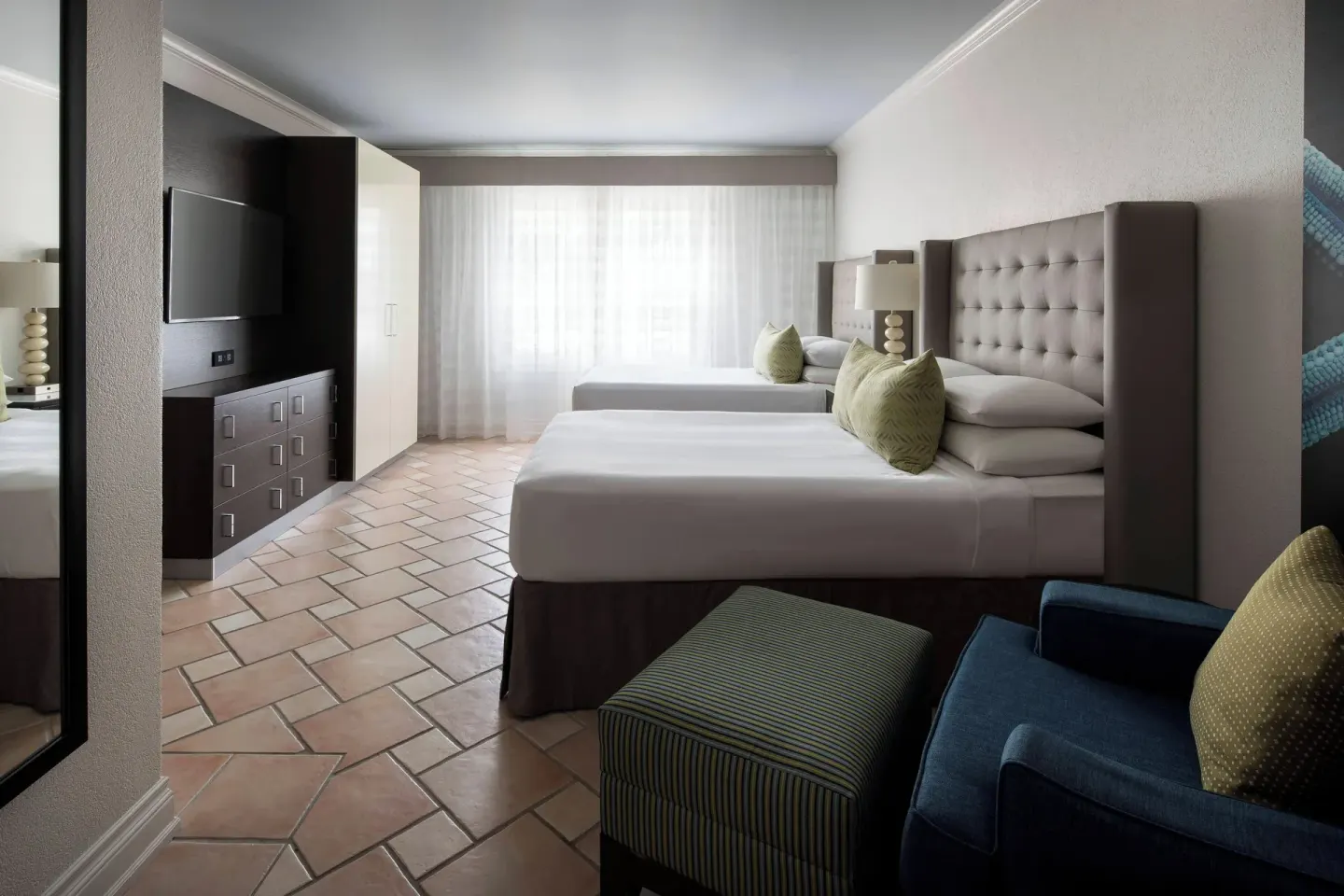 Guest room with two beds, TV, armchair, and tiled floor at St Kitts Marriott Beach Resort, Casino & Spa.