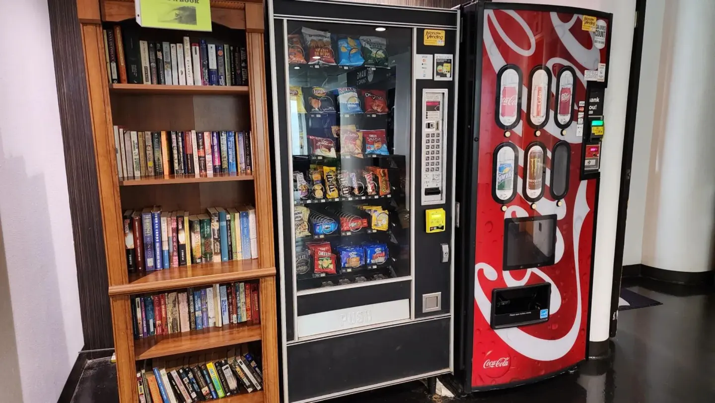 Bookcase and snack and drink vending machines inside Stay Hotel Waikiki.