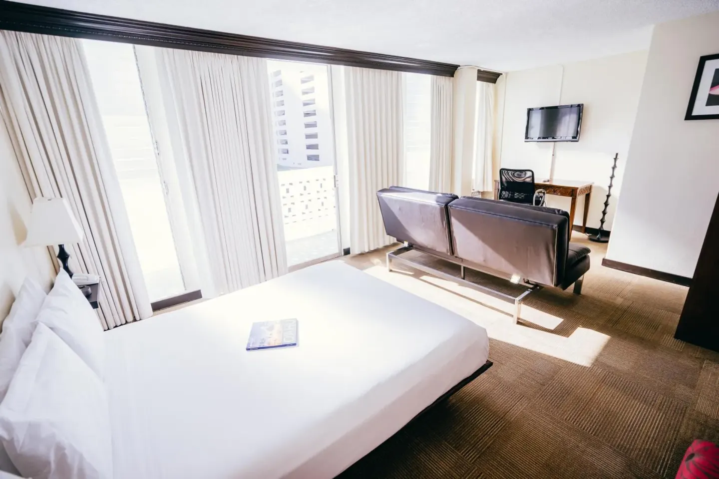 Guest room at Stay Hotel Waikiki with a king bed, large windows, sofa seating, and wall TV.