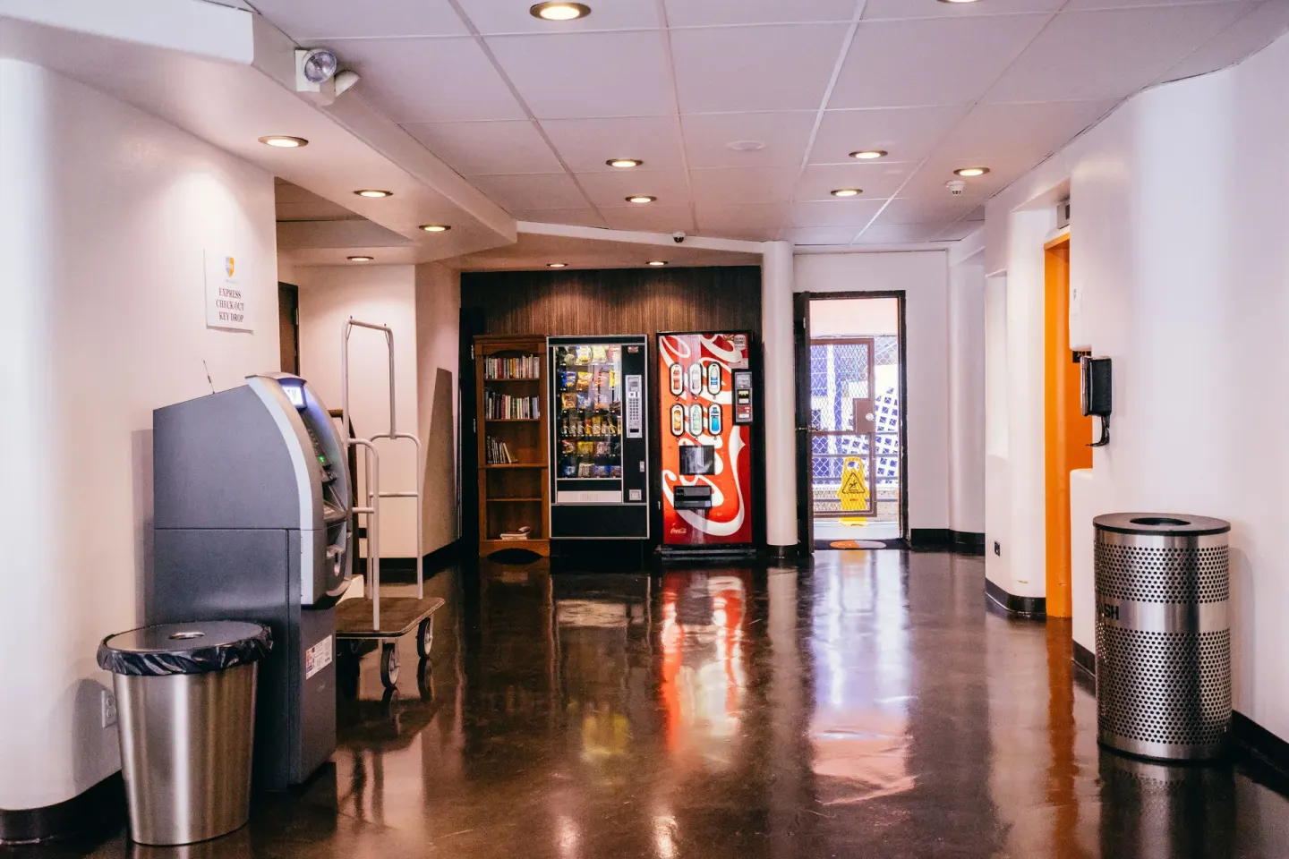 Lobby hallway with ATM, vending machines, and bookshelves at Stay Hotel Waikiki.