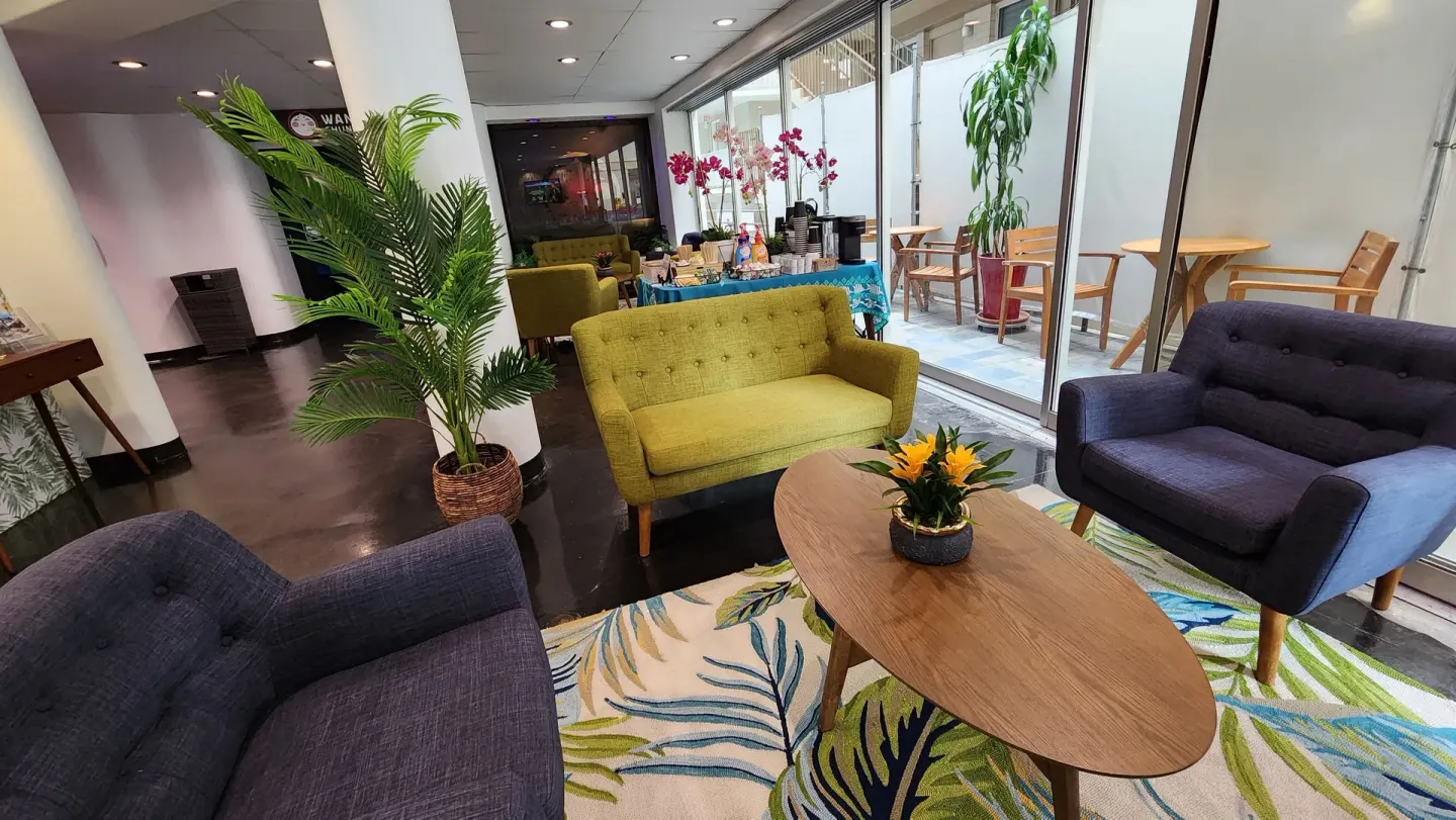 Lobby lounge with sofas, plants, and patio doors at Stay Hotel Waikiki.