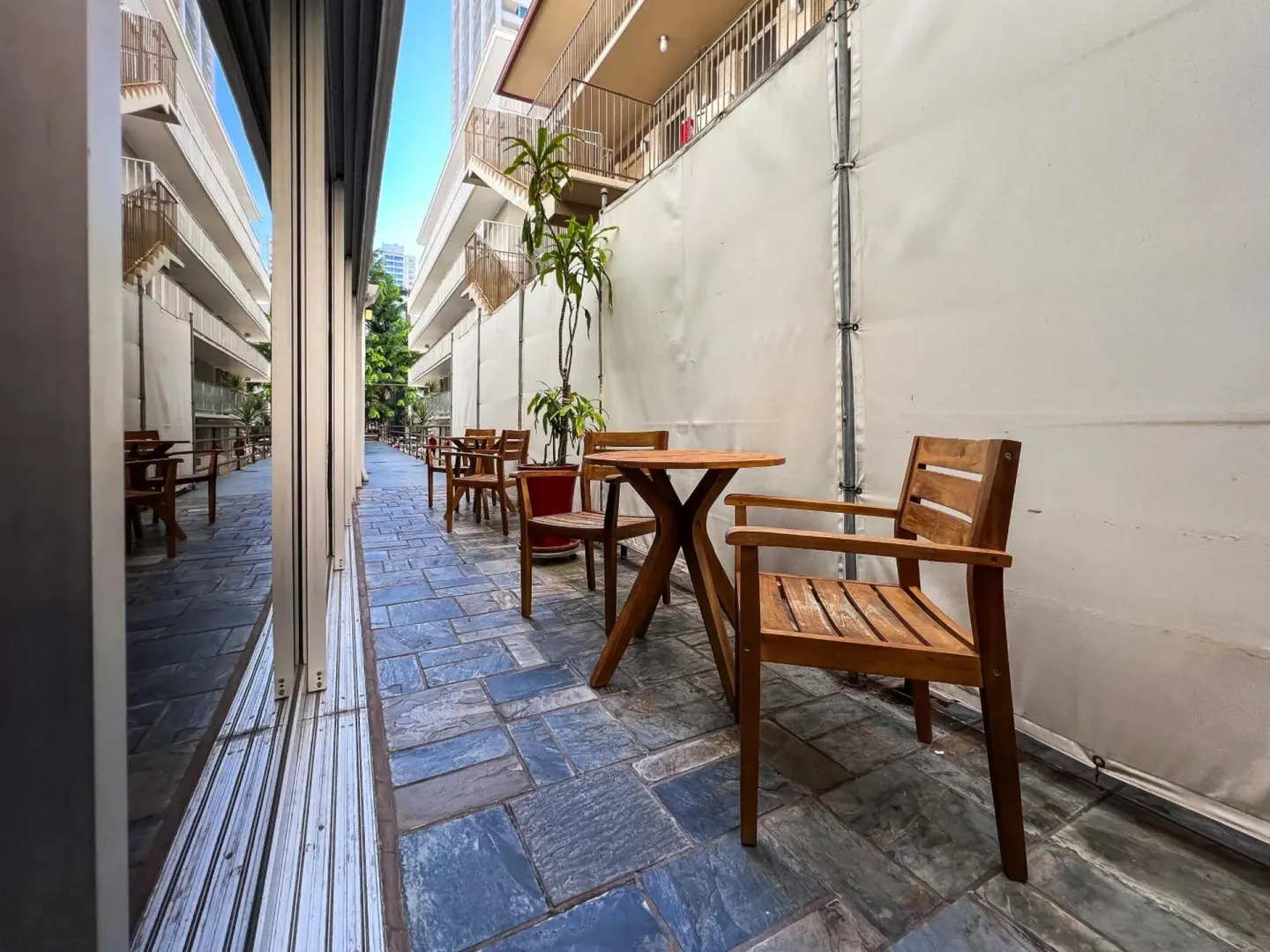 Outdoor patio with wooden tables and chairs at Stay Hotel Waikiki.