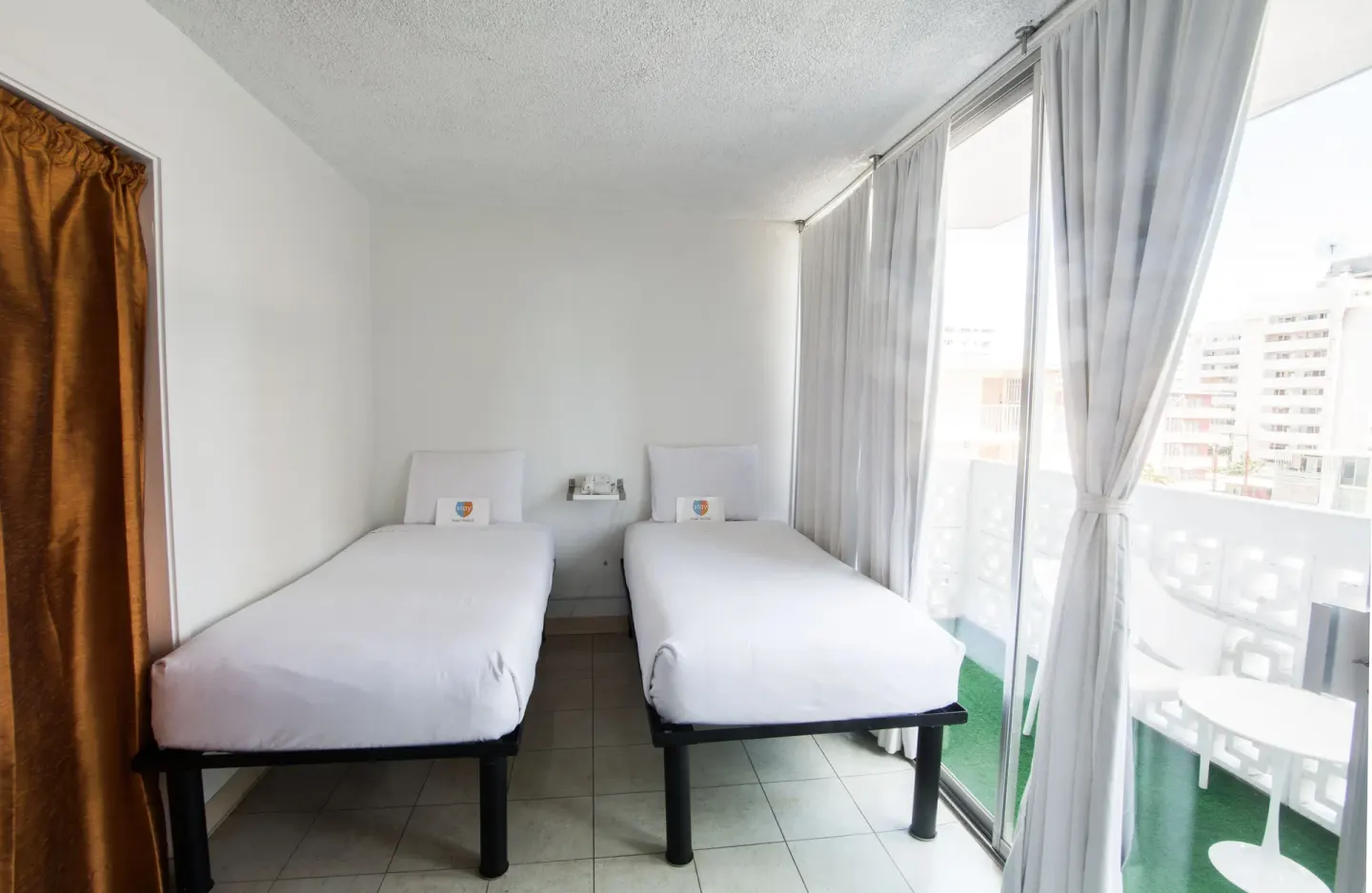 Two twin beds next to sliding balcony doors in a guest room at Stay Hotel Waikiki.