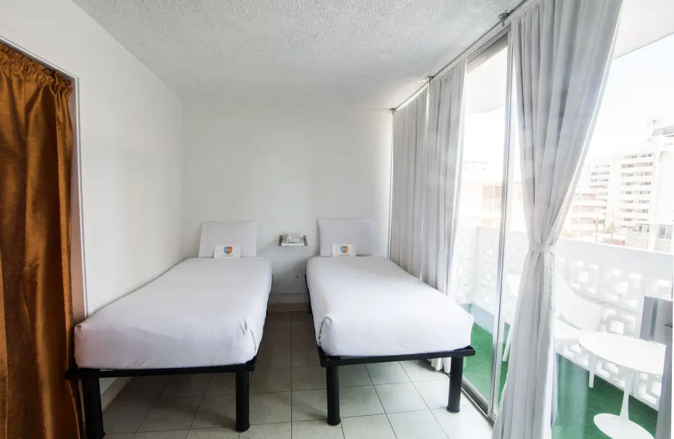 Two twin beds next to sliding balcony doors in a guest room at Stay Hotel Waikiki.