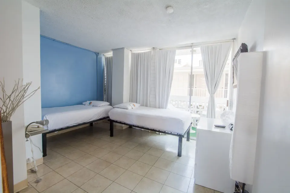 Two twin beds in a bright guest room with balcony doors at Stay Hotel Waikiki.