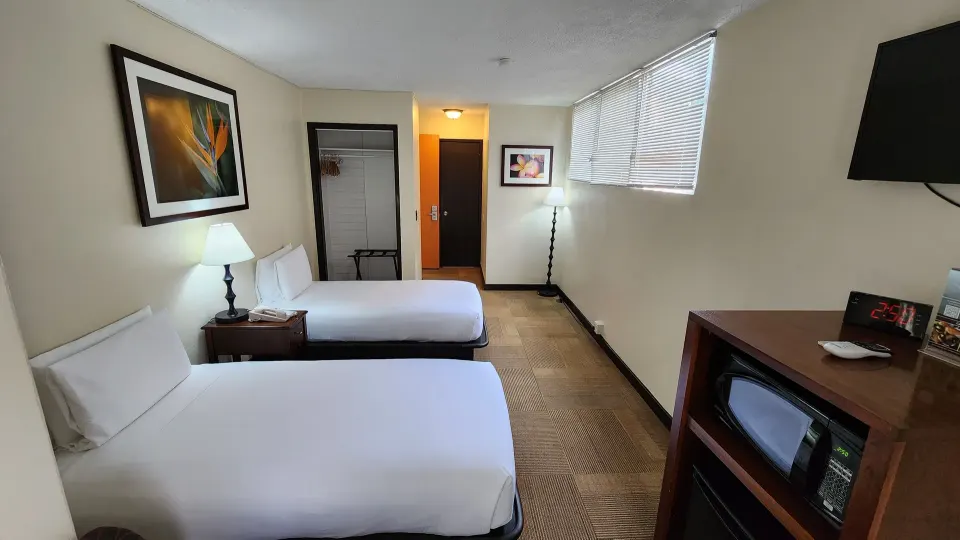 Two twin beds with wall art, blinds, TV, and cabinet appliances at Stay Hotel Waikiki.