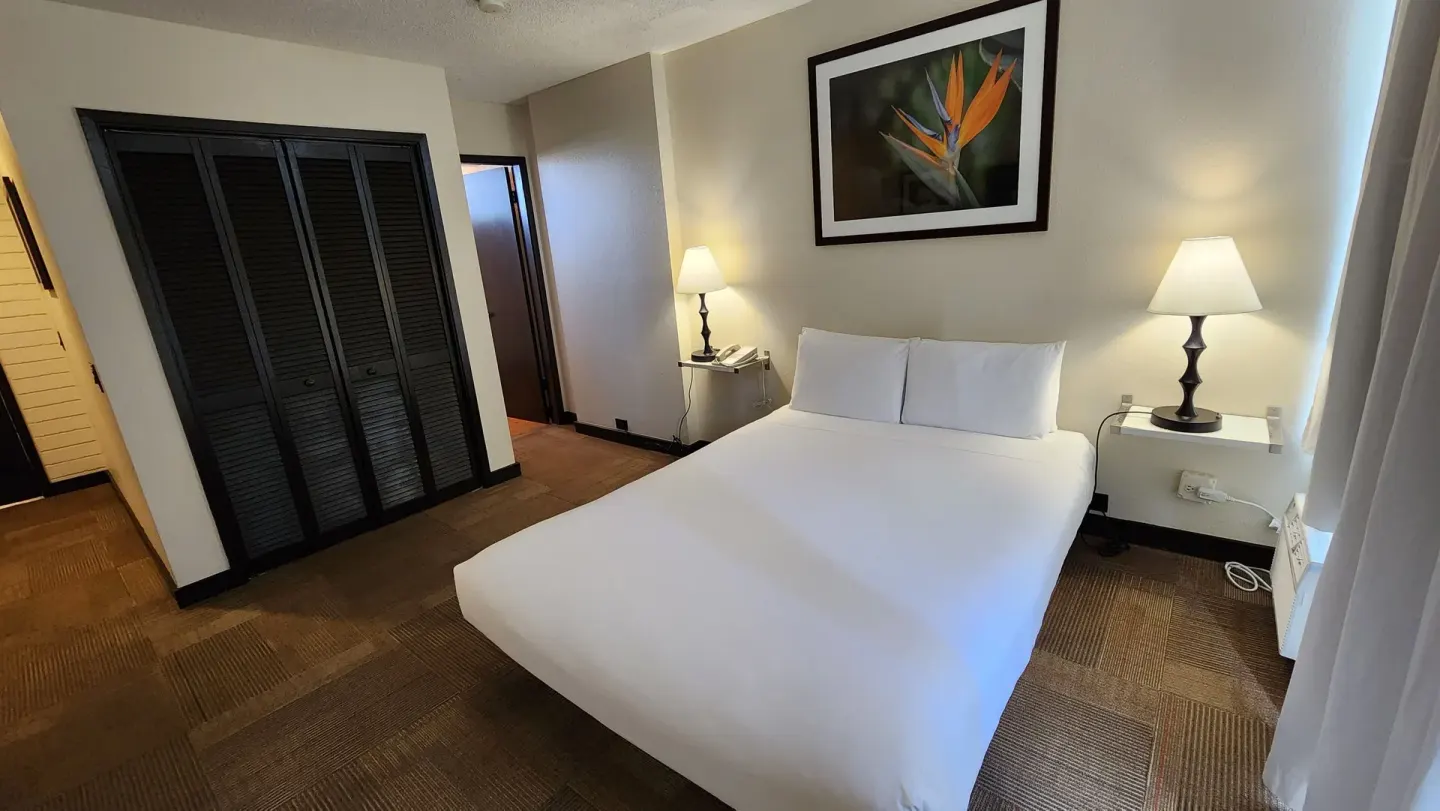Boutique Room queen bed with bedside lamps and closet at Stay Hotel Waikiki.