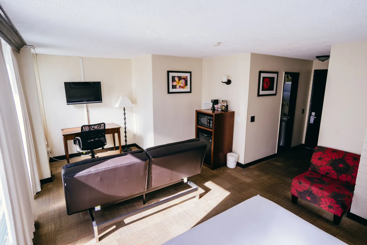 Deluxe Room with sofa bed, desk, wall TV and red chair at Stay Hotel Waikiki.